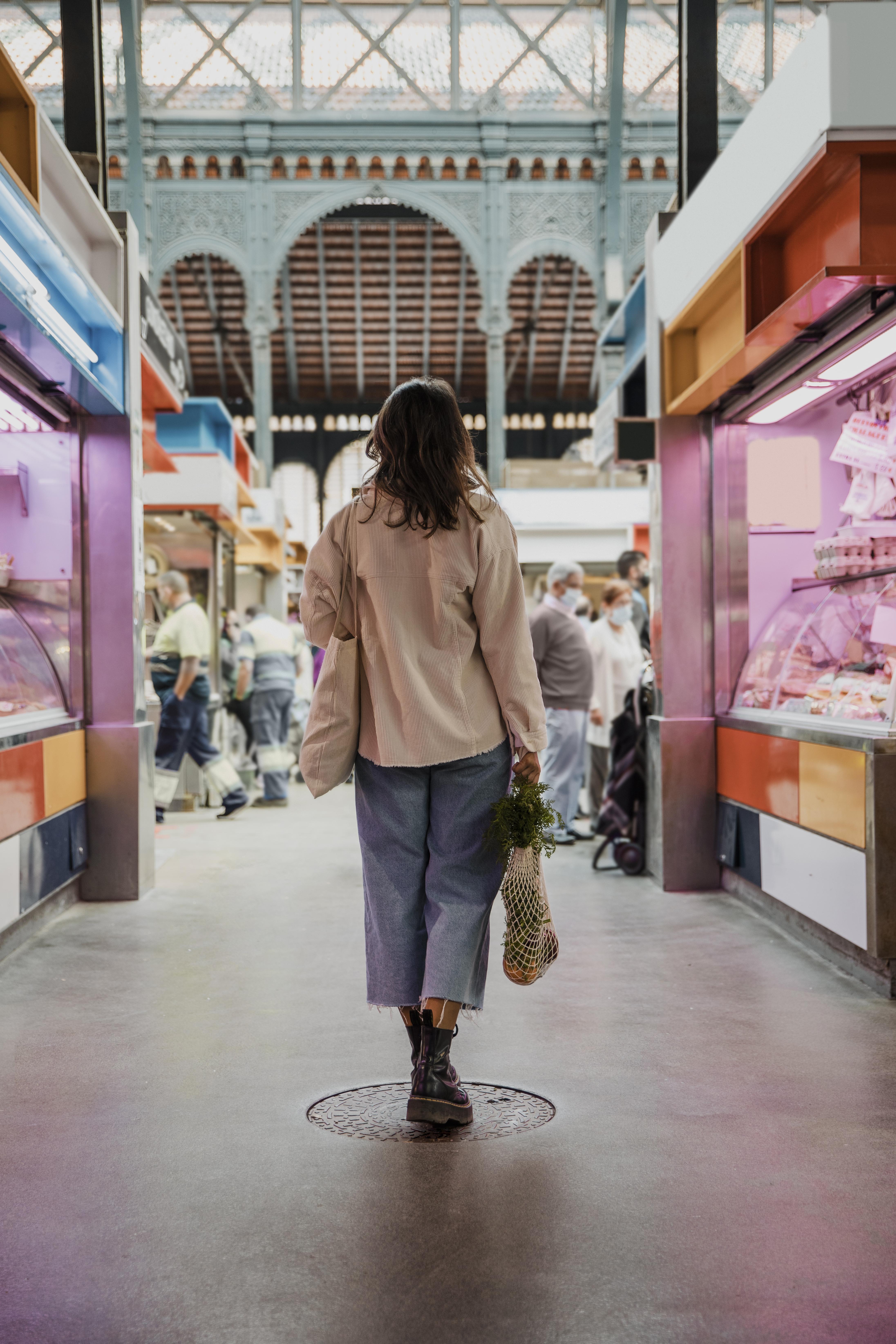 A woman walks through Sant Antoni market in Barcelona, passing stalls selling food. Photo courtesy of www.freepik.com. 