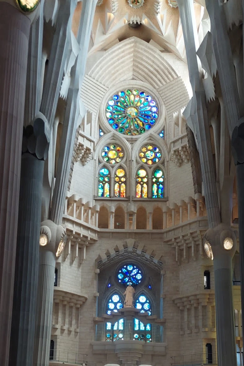 The interior of the Sagrada Familia basilica in Barcelona showing the vibrant stained-glass windows casting colourful light inside. Photo © Dugald Steer 2024.